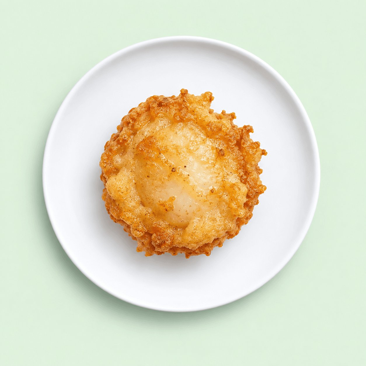 Golden battered jumbo scallop on a white plate