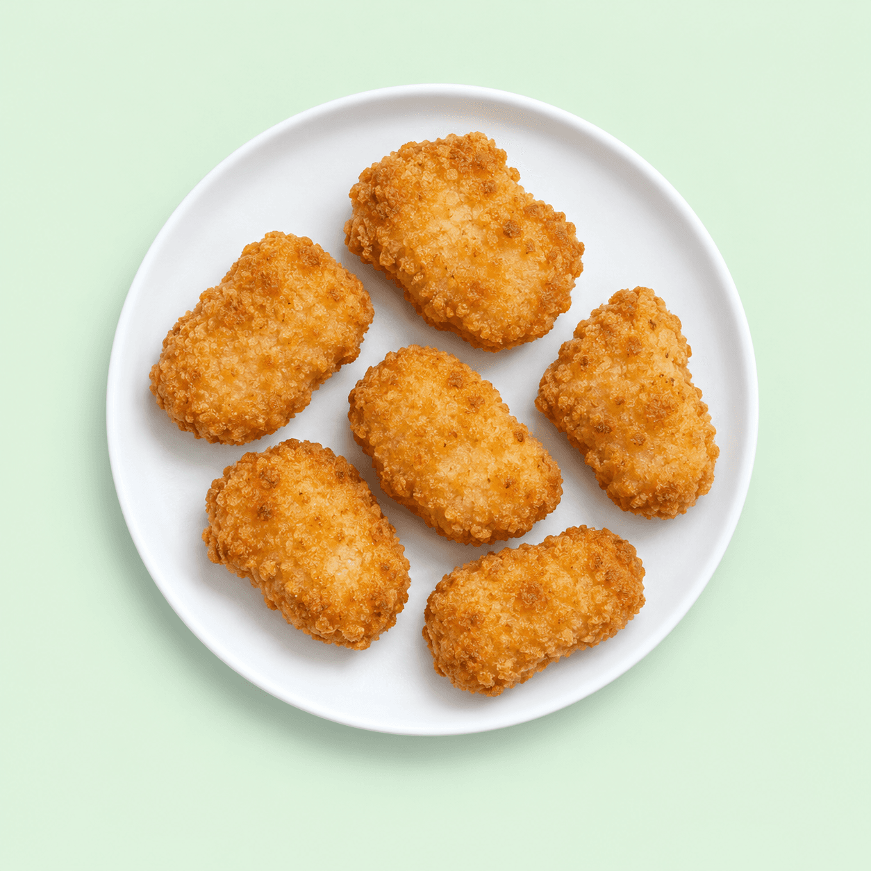 Six golden chicken nuggets on a white plate